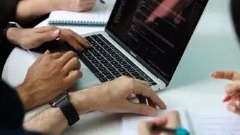Grupa ludzi pracująca przy biurku nad projektem