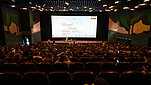 Wielka sala kinowa z ekranem pokazująca konferencje